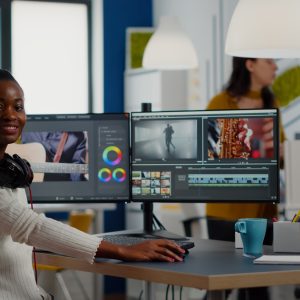 African video editor looking at camera smiling editing video project
