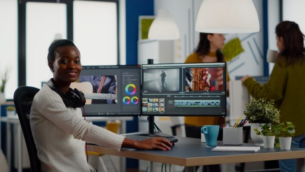 African video editor looking at camera smiling editing video project